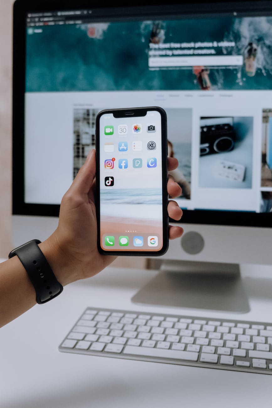 holding a smartphone in front of an imac