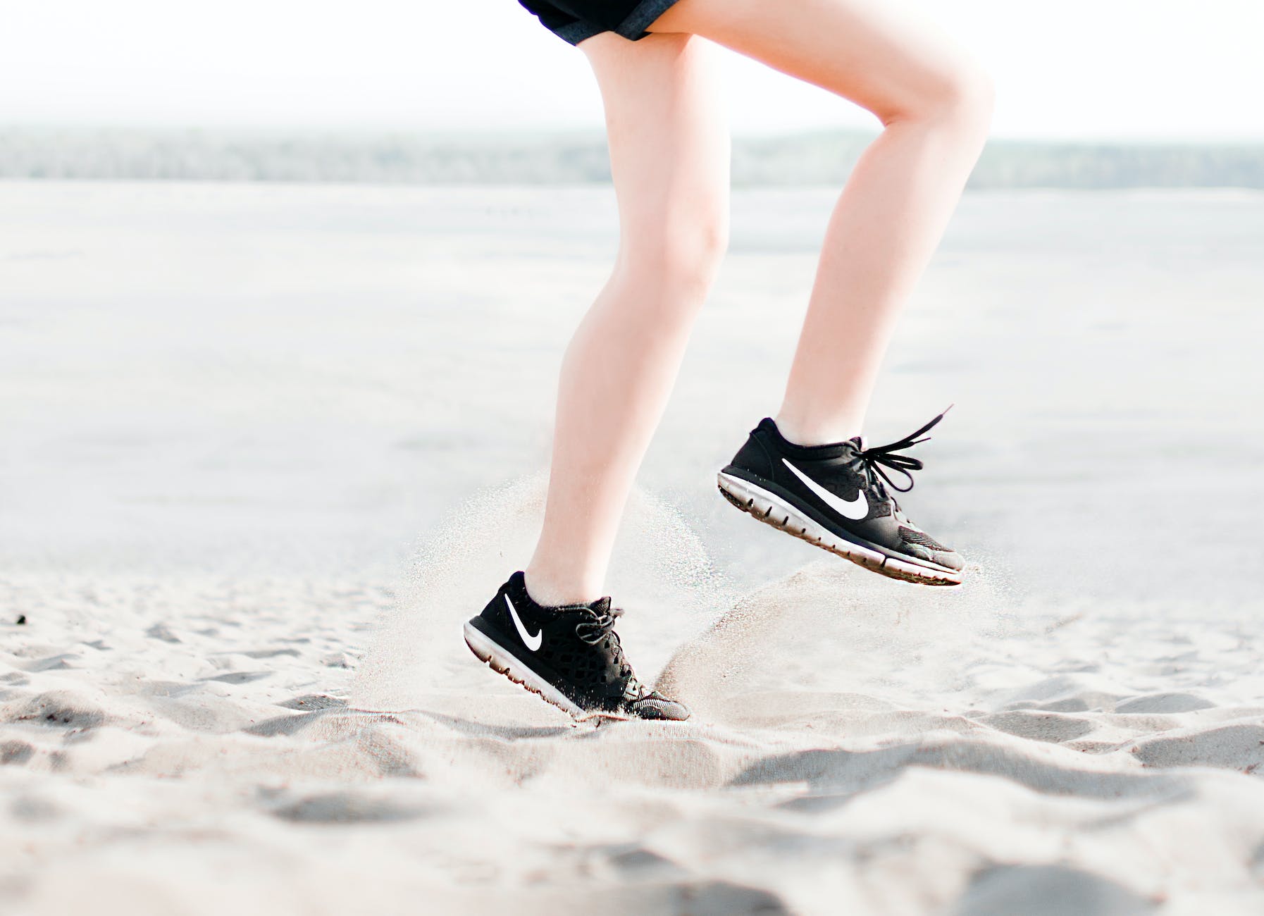 photo of woman wearing pair of black nike running shoes