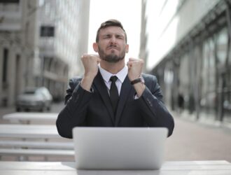 man in black suit sitting on chair beside buildings